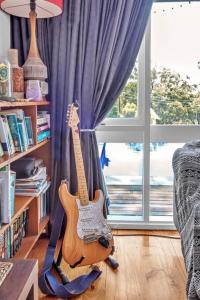 a guitar sitting in a living room next to a window at Nature's Edge - A Parkland Escape for Families in Adelaide