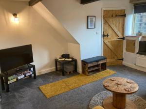 a living room with a tv and a sliding barn door at Coiners Rest in Heptonstall