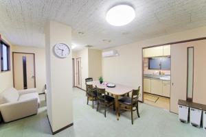 ein Esszimmer und eine Küche mit einem Tisch und einer Uhr in der Unterkunft ホテルよしや in Osaka
