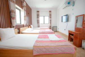 um quarto de hotel com três camas e uma televisão em KHÁNH GIA HOTEL em Tam Kỳ