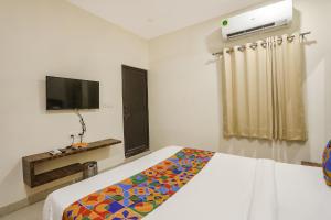 a bedroom with a bed and a flat screen tv at FabHotel Prince Mama in Gwalior