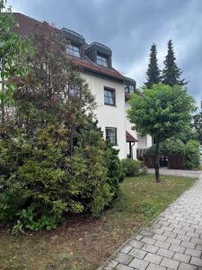uma grande casa branca com uma árvore em frente em Cozy&spacious topfloor apartment em Schwaig bei Nürnberg