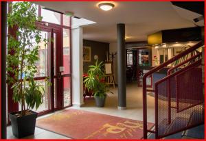 a hallway with potted plants and a staircase in a building at Hôtel du Parc Limoges & Restaurant "Le temps d'une pause" in Limoges