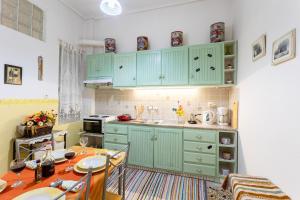 a kitchen with green cabinets and a table with chairs at Sofi's Flat in the city center, 5min to the sea in Kalamata