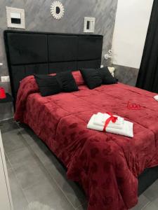 1 dormitorio con 1 cama roja y 2 toallas blancas en La Rosa home, en Nápoles