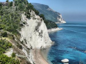 a rocky cliff next to the ocean with a beach at Rinaldi's Apartment in Sirolo