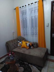 Experience Euphoria, Gish Apartments في مومباسا: غرفة معيشة مع أريكة بنية اللون وستائر برتقالية