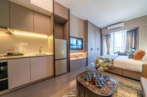 Cet appartement comprend une chambre avec un lit et une cuisine avec une table. dans l'établissement Millenia Executive Apartment - Guangzhou East Railway Station Zhujiang New Town Branch, à Canton
