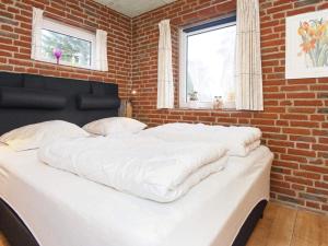 a large white bed in a room with a brick wall at Holiday home Sydals XCIV in Skovmose