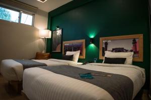 twee bedden in een hotelkamer met groene muren bij LOKAL Rooms x Lahore (Cavalry) in Lahore