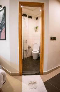 a bathroom with a toilet and a shower with a pair of slippers at LOKAL Rooms x Lahore (Cavalry) in Lahore