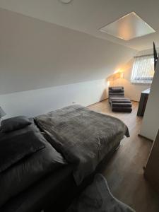 a bedroom with a large bed and a chair at Waldheimatblick in Sankt Kathrein am Hauenstein