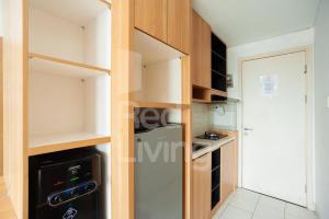 a small kitchen with wooden cabinets and a stove at RedLiving Apartemen Patra Land Urbano - Iconic Room Tower Mid-West in Bulanbulan