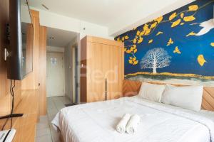 a bedroom with a bed with a painting on the wall at RedLiving Apartemen Patra Land Urbano - Iconic Room Tower Mid-West in Bulanbulan