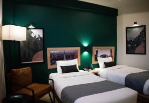 um quarto de hotel com duas camas e uma parede verde em LOKAL Rooms x Lahore (Cavalry) em Lahore