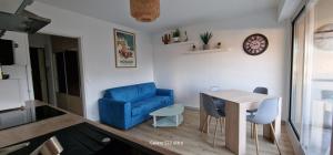HOME ET HOLIDAY Le Petit Manseng في نيس: غرفة معيشة مع كرسي ازرق وطاولة