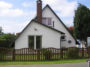 een wit huis met een houten hek bij Ferienhaus Heimathafen in Friedrichskoog-Spitz