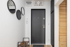 a hallway with a black door and a mirror at Apartment Near the Warta River by Renters in Poznań