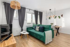 ein Wohnzimmer mit einem grünen Sofa und einem TV in der Unterkunft Apartment Near the Warta River by Renters in Posen