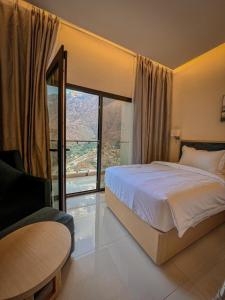 a bedroom with a bed and a large window at Season Inn Hotel_Bald Sayt in Rustāq