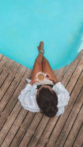 a woman laying on a wooden deck next to the water at De Zeekoe Guest Farm in Oudtshoorn