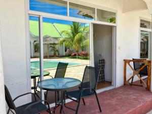 een patio met een tafel en stoelen en een zwembad bij Sunrise Villas in Jambiani