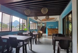a dining room with tables and chairs and windows at Amos Pili Tree Inn powered by Cocotel in El Nido