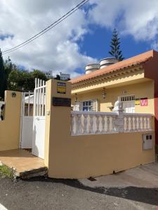 una casa amarilla con una valla blanca y una puerta en Casa Juana, en Agua de Fontanales
