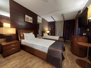プレヴェンにあるHotel City Plevenのベッド2台とテーブルが備わるホテルルームです。