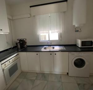 a white kitchen with a sink and a microwave at Apartamento Plaza Grande in Zafra