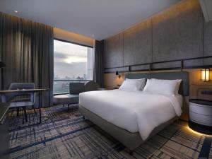 um quarto de hotel com uma cama grande e uma janela grande em Mercure Surabaya Manyar em Surabaya