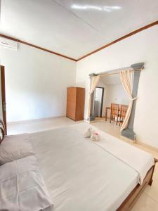 ein großes weißes Bett in einem Zimmer mit einem Tisch in der Unterkunft Suris bungalows in Buleleng