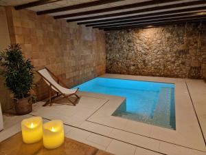una piscina en una habitación con silla y silla en CAN BUFÍ Espectacular casa con piscina interior, en Llagostera