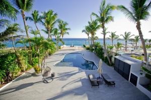 una piscina con palme e l'oceano di TRACADERO Beach Club & Holidays Rentals a Bayahibe Altre 37 foto