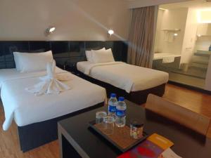 a hotel room with two beds and a table with drinks at Alia Premier KLCC in Kuala Lumpur