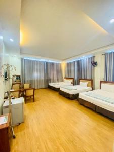 Cette grande chambre comprend deux lits, une table et des chaises. dans l'établissement Hương Sen Hotel Bac Giang, à Bắc Giang