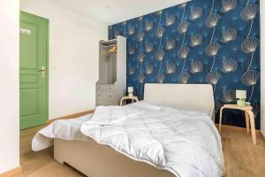 ein Schlafzimmer mit einem Bett und einer blauen Wand in der Unterkunft Maison spacieuse proche Lille in Roubaix