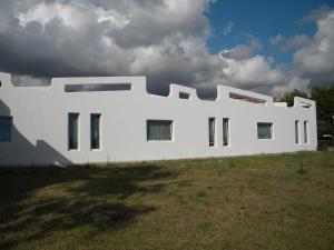 a white building with windows on a grass field at HOTEL GENOVA in Scalea