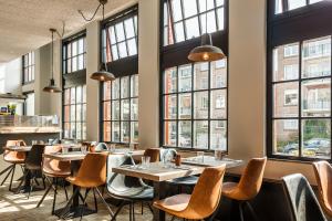 a restaurant with tables and chairs and windows at Hotel Bleecker in Bloemendaal