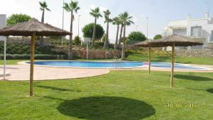 uma piscina com guarda-sóis num quintal em PLANTA BAJA CAPRI VISTABELLA GOLF 41 em Alicante