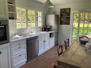 eine Küche mit weißen Schränken und einem Holztisch in der Unterkunft Noyer in Thil-Manneville