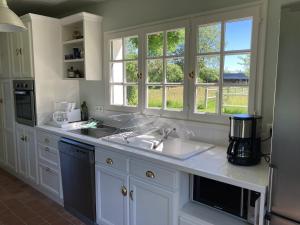 una cocina con armarios blancos, fregadero y ventanas en Noyer, en Thil-Manneville 36 fotos más