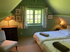 Un dormitorio con dos camas y una ventana y una silla. en Noyer, en Thil-Manneville