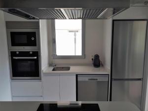 cocina con armarios blancos, fregadero y ventana en Los Dolses Mirador Apartments 2 beds, en 
