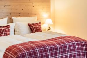 two beds in a bedroom with a plaid blanket at Das Achental Resort in Grassau