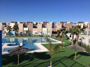 un complejo con piscina, palmeras y un edificio en Apto Atico Aguas Nuevas Torrevieja, en Torrevieja