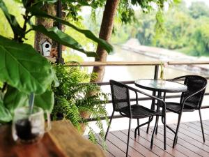 eine Terrasse mit 2 Stühlen und einem Tisch auf einer Terrasse in der Unterkunft Rimwang The River Life in Sai Yok