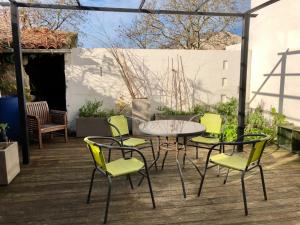 un patio con mesa y sillas en una terraza en Charmante maison à Jard sur mer sur la côte vendéenne en Jard-sur-Mer