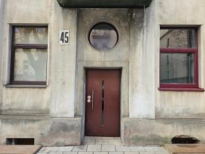 um edifício com uma porta vermelha e duas janelas em Centre kambarys su didele lova #1 em Kaunas