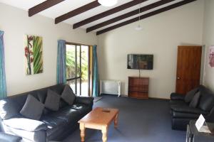 a living room with a black leather couch and a table at Central & Relaxing in Franz Josef